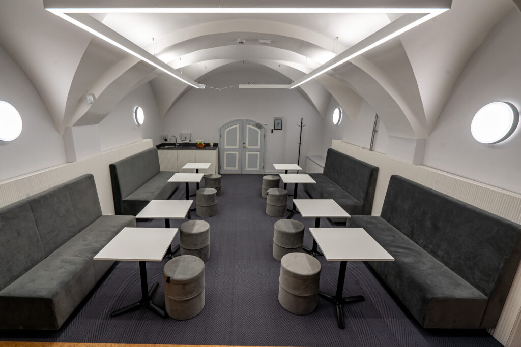 Valge võlvruum hallide pinkide ja valgete laudadega