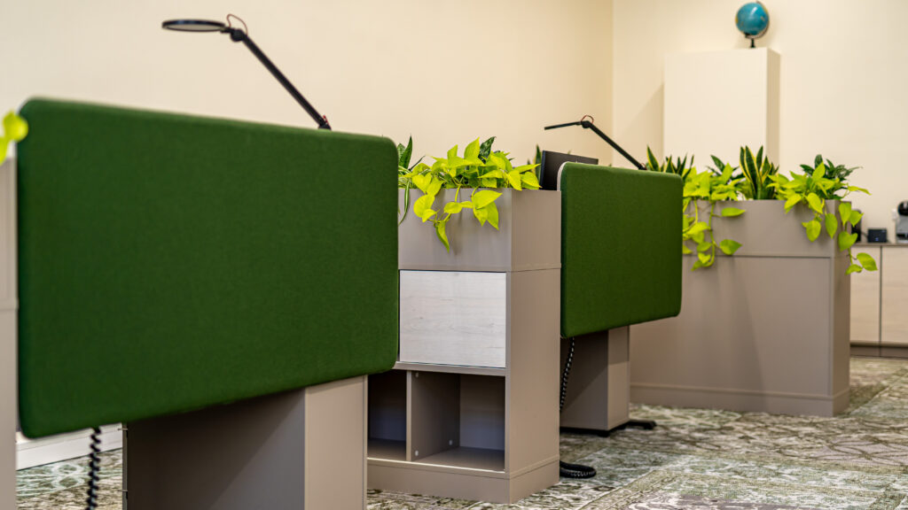 Roheliste paneelidega töökohad, mida eraldavad lopsakad taimekastid