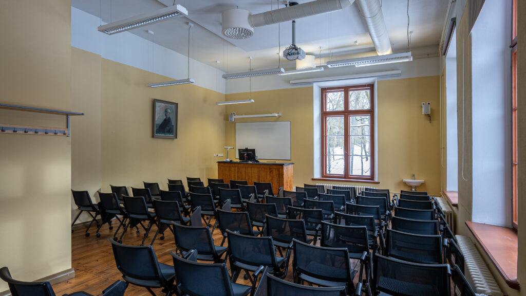 Kollaste seintega klassiruumi vaade ridade kaupa mustade toolidega