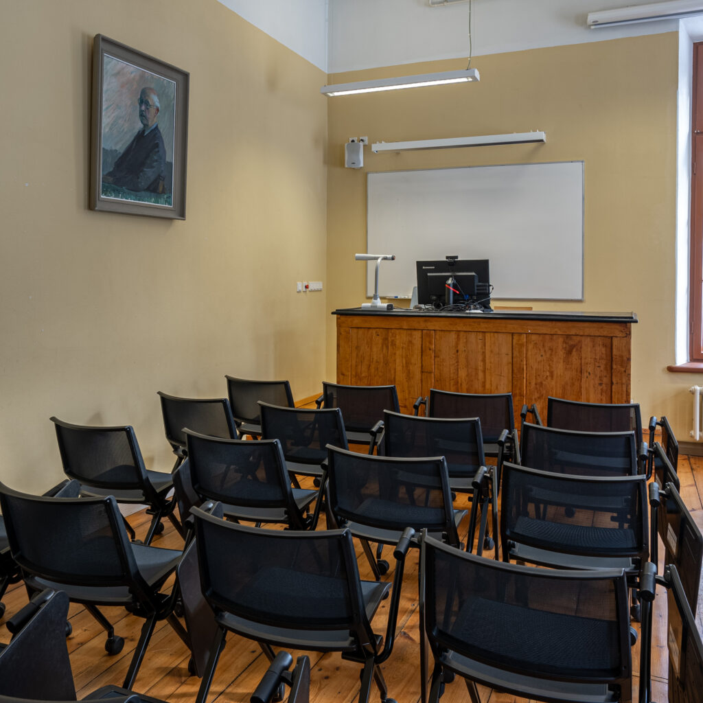 Klassiruum: puitpult, mustad toolid, hele tahvel