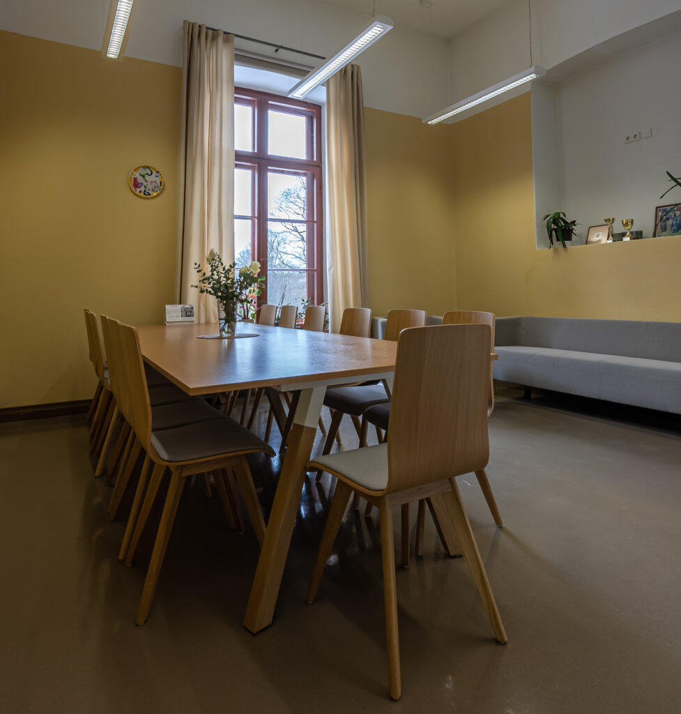 Valgus ja avar nõupidamisruum pika laua ja mugavate puidust toolidega